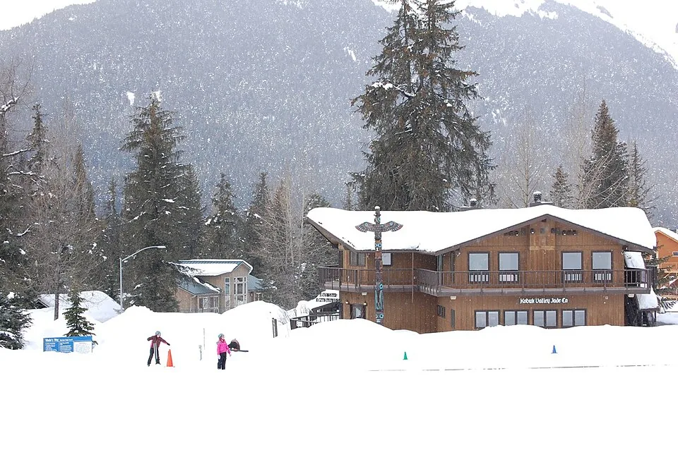 Snow-covered buildings and skiers at the base of Alyeska Resort, Alaska.