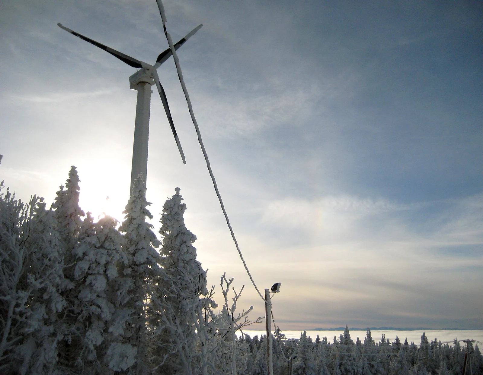 A wind turbine above snow-covered forest at Bolton Valley, Vermont.