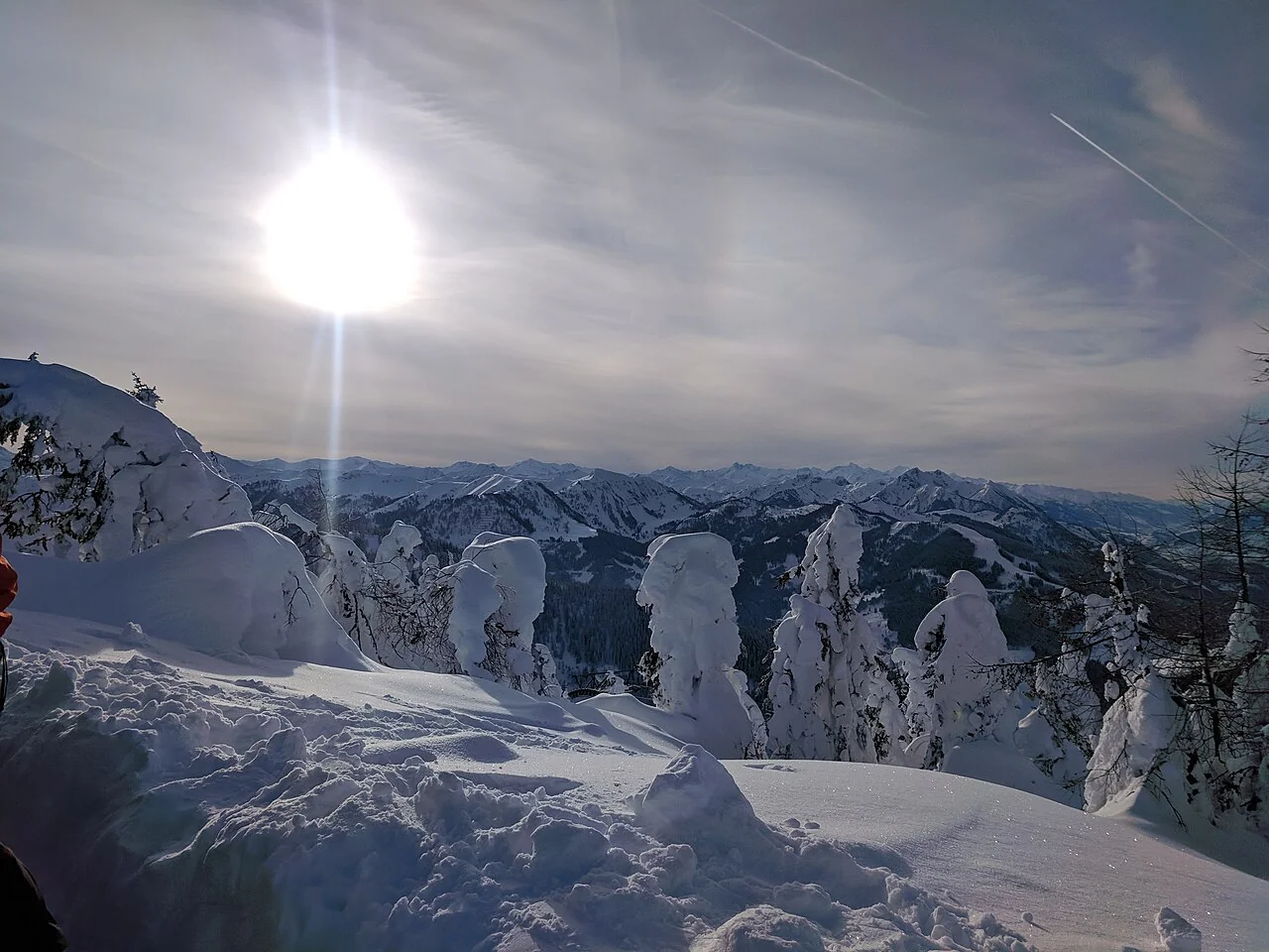 Snow-covered trees and mountain ridges beneath the winter sun at Flachau.
