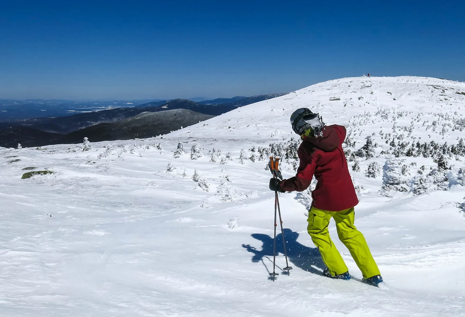 A skier on a sunny snow-covered slope at Saddleback Mountain, Maine.