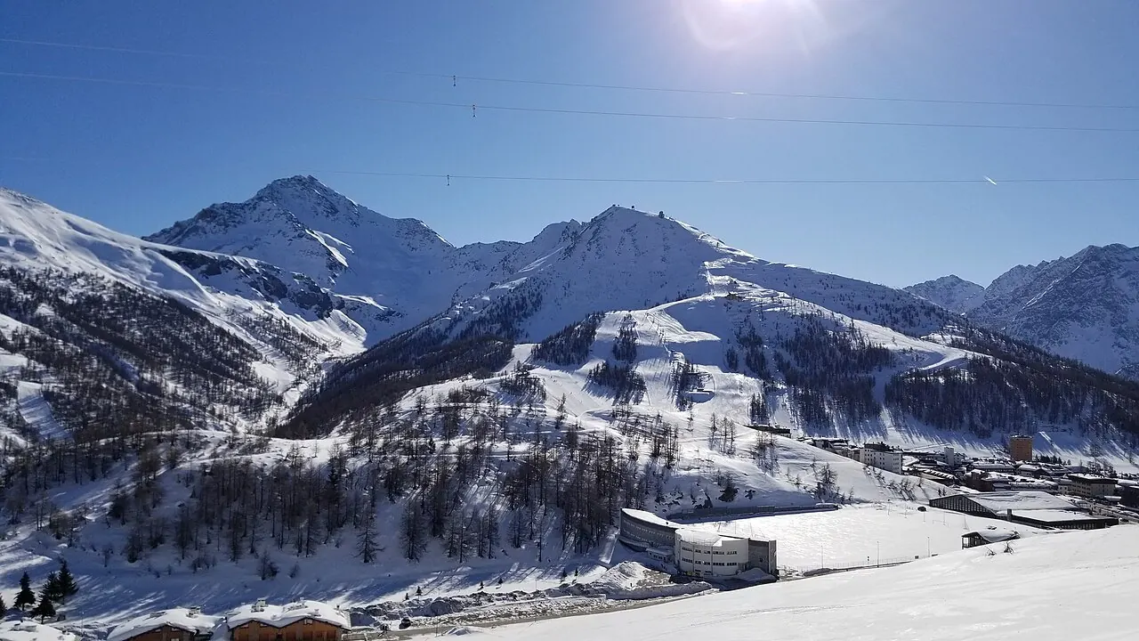 Mount Sises (to the right) and Mount Rognosa (to the left) as viewed from the lower slopes of Mount Fraiteve. The town of Sestriere, Italy is in the foreground to the right of the image. Mount Sises hosts a major portion of the Sestriere ski resort within the larger Via Lattea ski area.