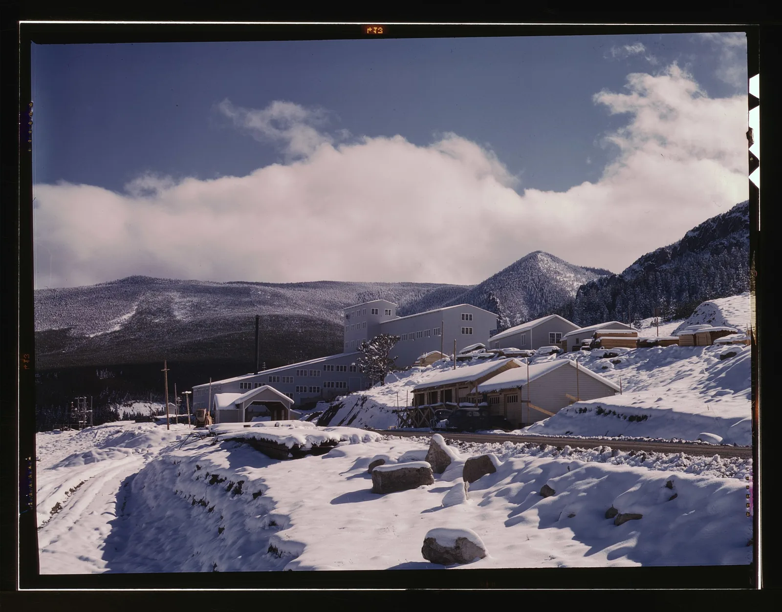 An archival photograph of snow-covered buildings and hills in the Little Belt Mountains foothills, Montana, in 1942.